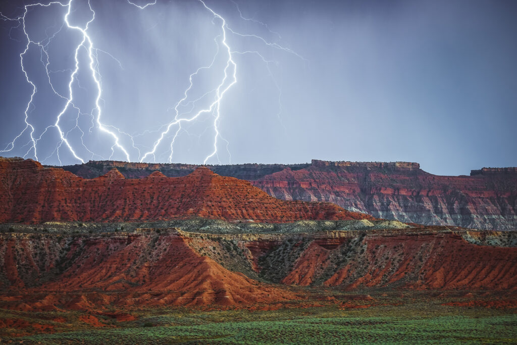 Intense lightning storm striking over red rock mountains, perfect for powerful marketing photo and video content creation. Ideal for showcasing bold and dynamic branding.